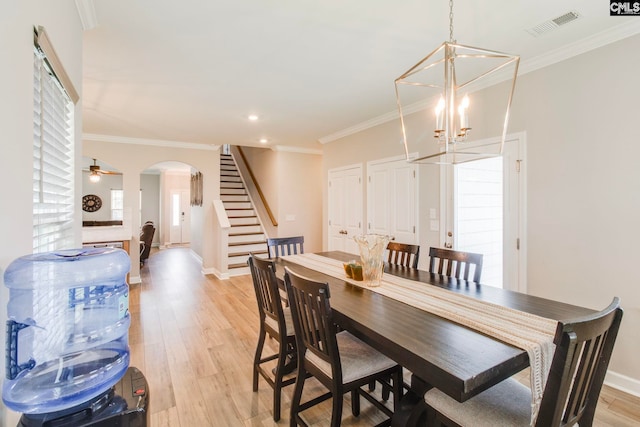 dining room with arched walkways, stairway, a chandelier, light wood-style floors, and baseboards