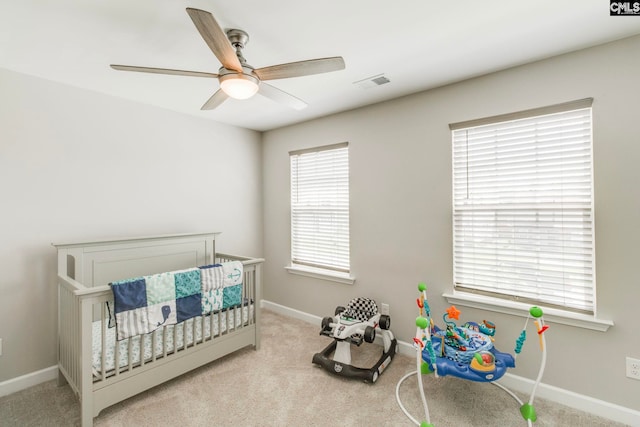 bedroom featuring baseboards, carpet floors, a ceiling fan, and a crib