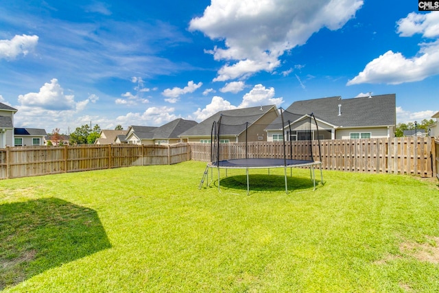 view of yard featuring a trampoline and a residential view