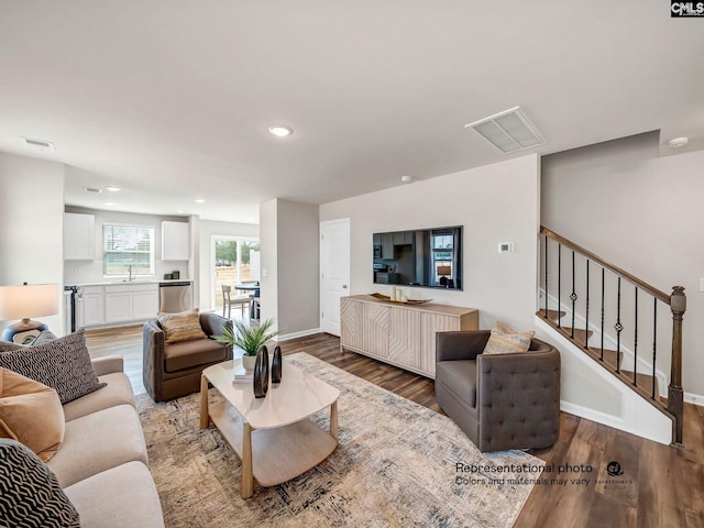 living room with wood finished floors, recessed lighting, baseboards, and stairs