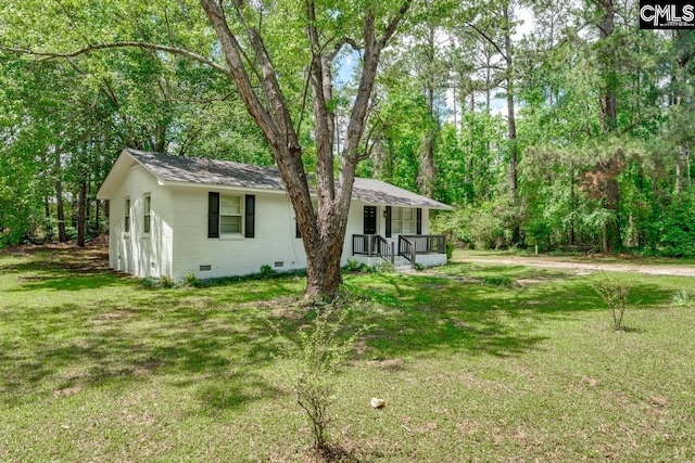 rear view of property with crawl space, covered porch, a lawn, brick siding, and roof with shingles