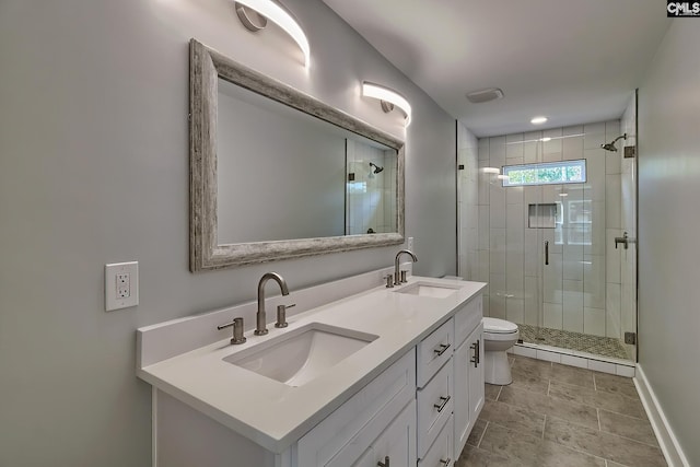 bathroom featuring toilet, a shower stall, double vanity, and baseboards