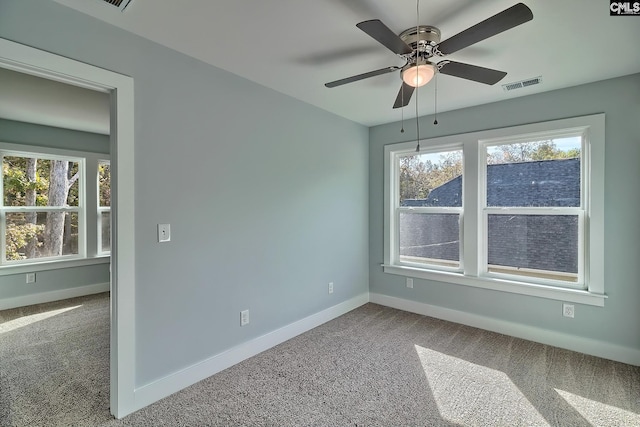 carpeted spare room featuring baseboards and a ceiling fan