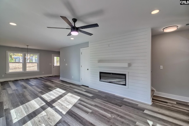 unfurnished living room featuring a ceiling fan, baseboards, wood finished floors, a large fireplace, and recessed lighting