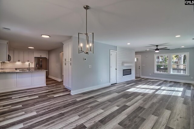 unfurnished living room with dark wood-style floors, baseboards, ceiling fan, recessed lighting, and a sink