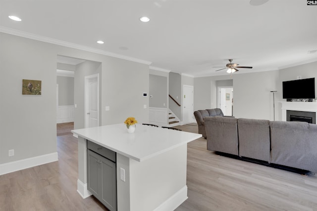 kitchen with gray cabinets, light wood-style flooring, a ceiling fan, a center island, and open floor plan