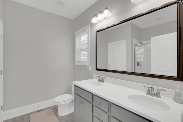 full bathroom featuring a shower stall, wood finished floors, toilet, and double vanity