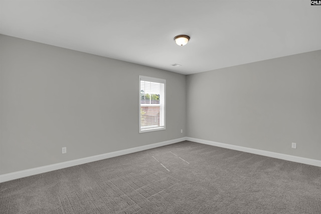 empty room featuring dark colored carpet and baseboards