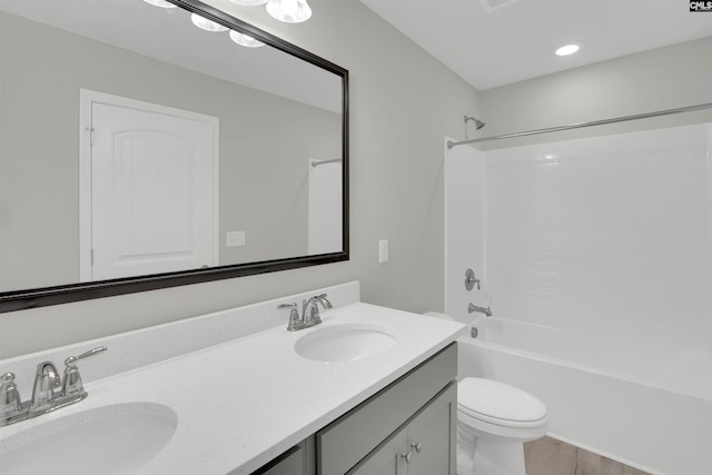 bathroom with toilet, double vanity, shower / tub combination, and wood finished floors