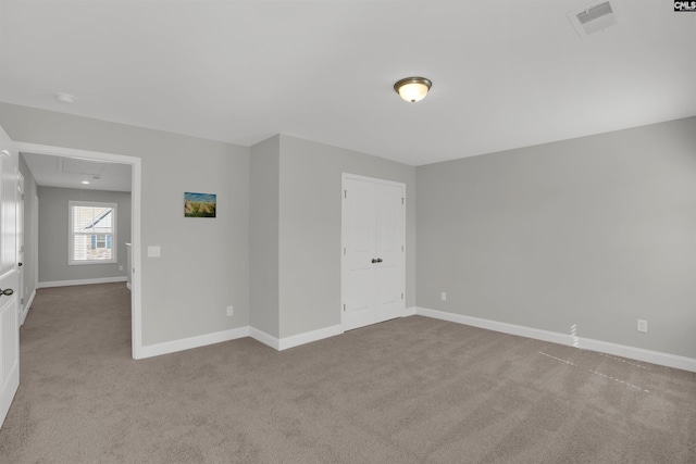 carpeted spare room featuring attic access and baseboards