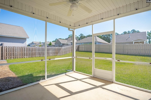 unfurnished sunroom with ceiling fan and a residential view