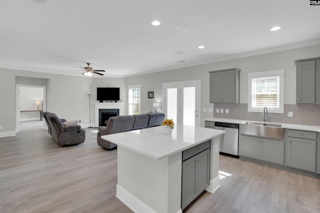 kitchen with gray cabinetry, stainless steel dishwasher, a sink, a ceiling fan, and light countertops