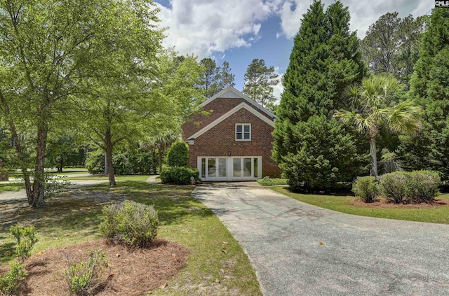 view of front of property with french doors, concrete driveway, and brick siding