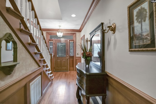 foyer featuring a wainscoted wall, light wood finished floors, stairway, crown molding, and recessed lighting