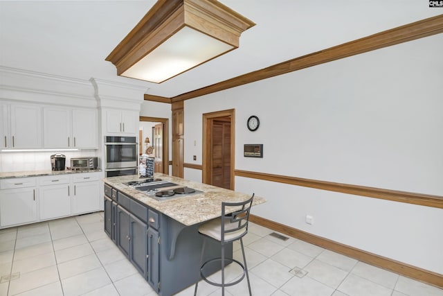 kitchen featuring white cabinetry, ornamental molding, stainless steel appliances, a kitchen island, and a kitchen breakfast bar
