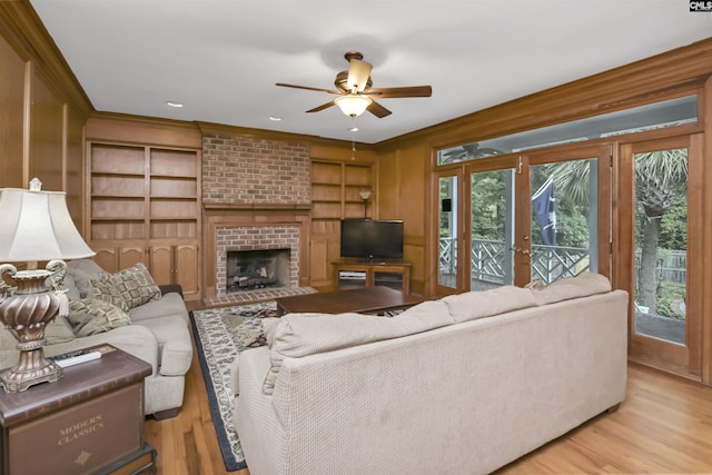 living area featuring plenty of natural light, a ceiling fan, light wood-type flooring, built in features, and ornamental molding