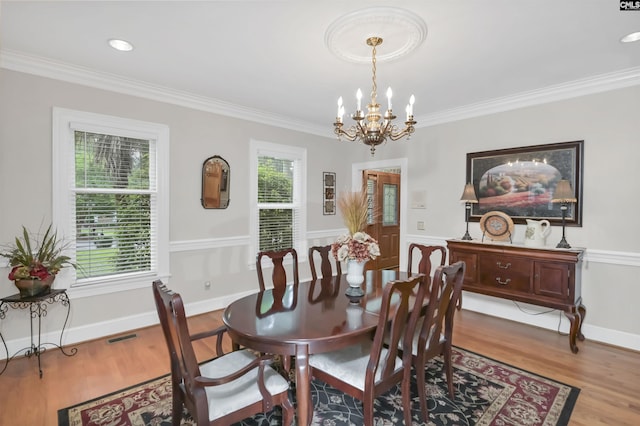 dining room with a chandelier, crown molding, light wood-type flooring, and baseboards