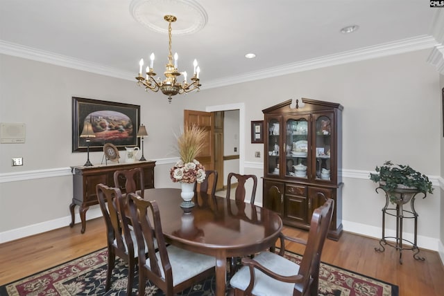 dining room with a chandelier, wood finished floors, crown molding, and baseboards