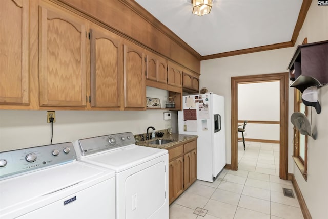 clothes washing area with washing machine and dryer, light tile patterned floors, crown molding, cabinet space, and baseboards