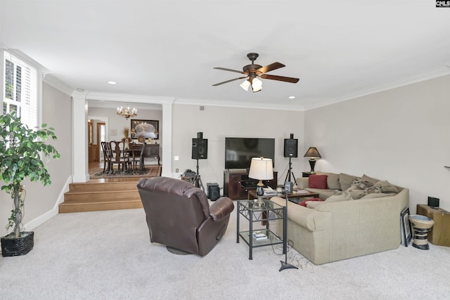 living area featuring decorative columns, crown molding, ceiling fan, carpet, and a chandelier