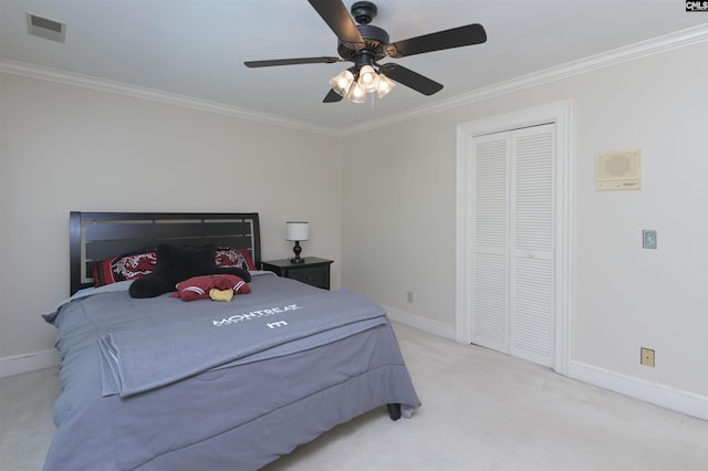 carpeted bedroom with ornamental molding, baseboards, ceiling fan, and a closet