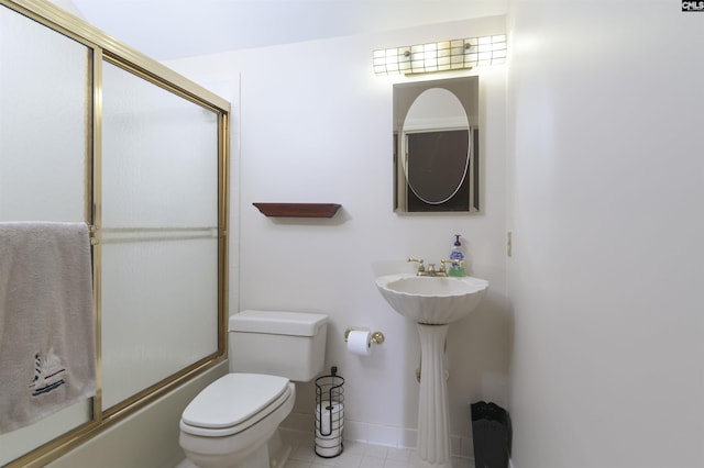 bathroom with toilet, bath / shower combo with glass door, tile patterned floors, and baseboards