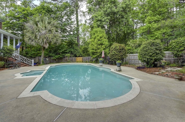 view of pool with a fenced backyard, a patio, view of wooded area, and a pool with connected hot tub