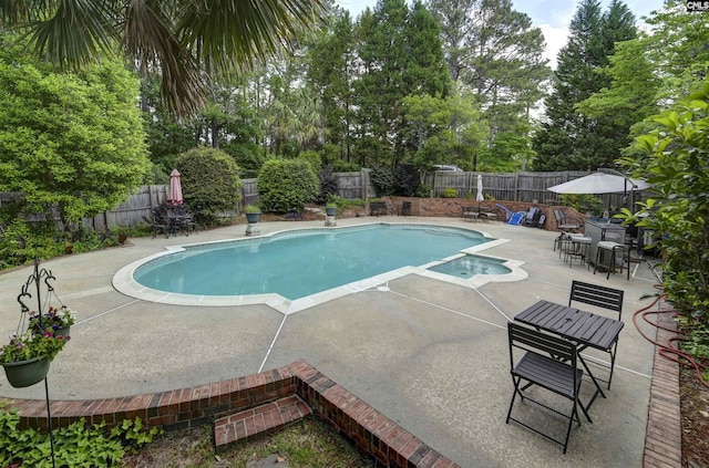 view of swimming pool featuring a patio area, a fenced backyard, view of wooded area, and a pool with connected hot tub