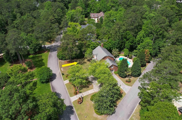 view of property location with a pool area and a heavily wooded area