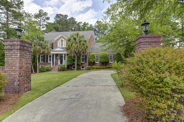 view of front of home featuring concrete driveway, a front yard, and brick siding