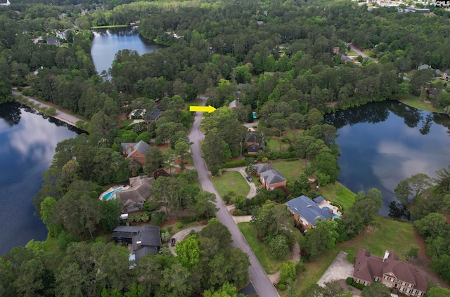 aerial overview of property's location with a large body of water, a heavily wooded area, and nearby suburban area