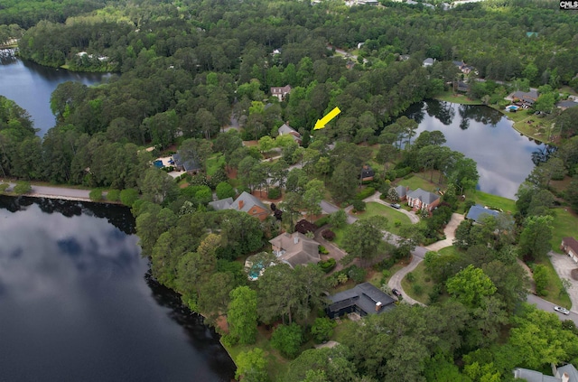 aerial view of property's location with a nearby body of water and a forest