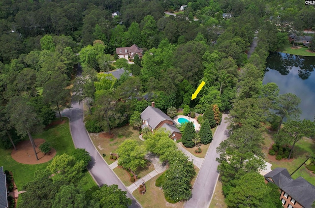 aerial view of property's location featuring a nearby body of water and a heavily wooded area