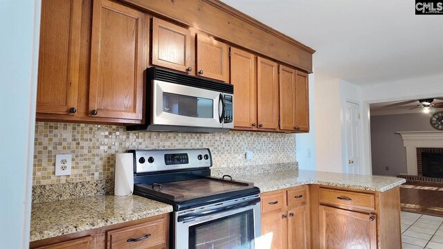 kitchen featuring appliances with stainless steel finishes, a ceiling fan, decorative backsplash, and a peninsula