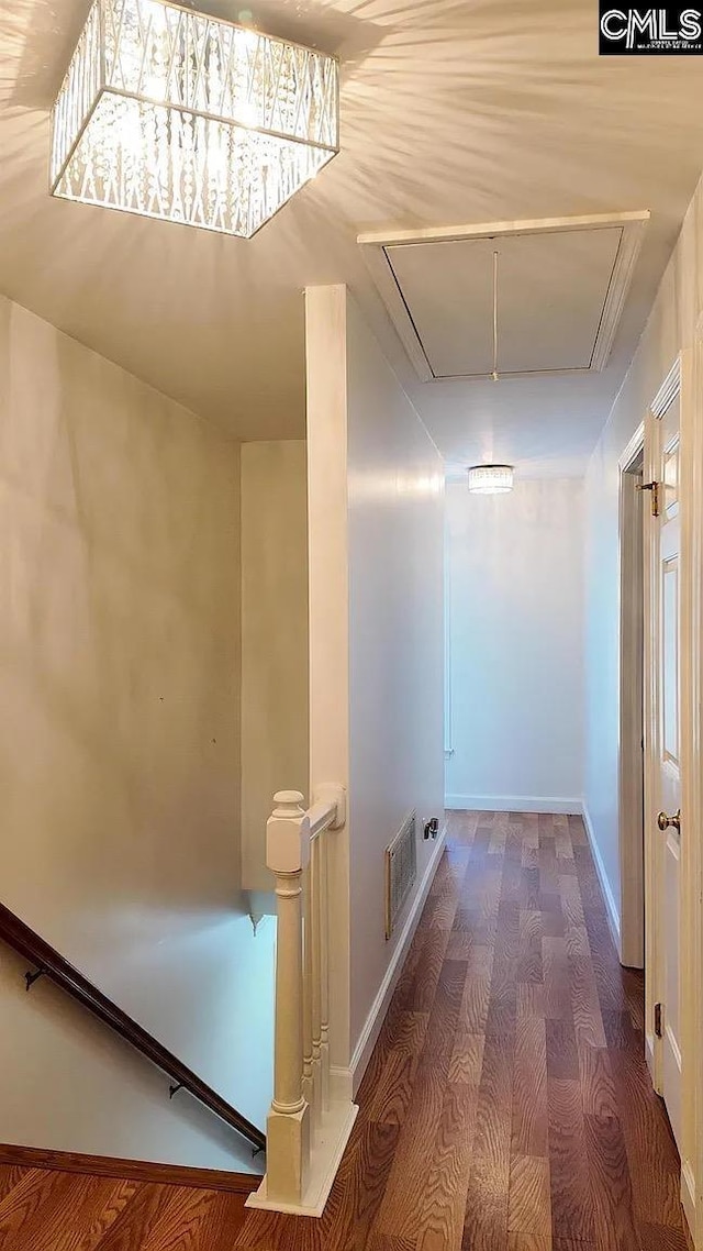 hallway with attic access, wood finished floors, an upstairs landing, and baseboards