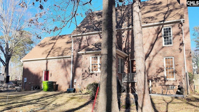 rear view of property with brick siding and a shingled roof