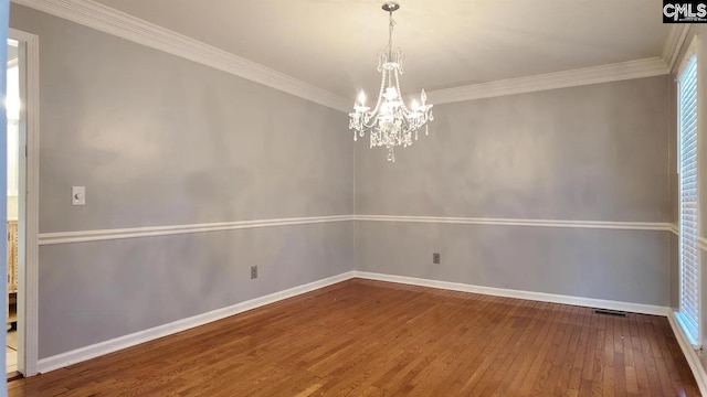 unfurnished room featuring a chandelier, hardwood / wood-style floors, baseboards, and crown molding