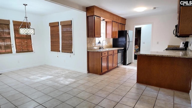 kitchen with appliances with stainless steel finishes, light tile patterned floors, backsplash, light stone counters, and a sink