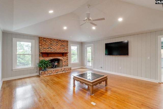 living room with a ceiling fan, baseboards, light wood finished floors, a fireplace, and lofted ceiling