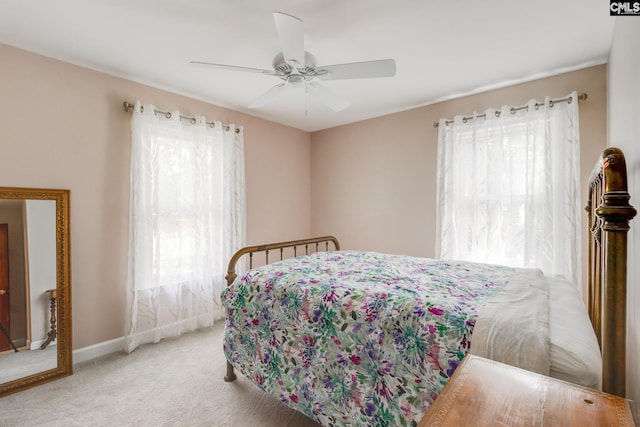 carpeted bedroom featuring multiple windows, baseboards, and a ceiling fan