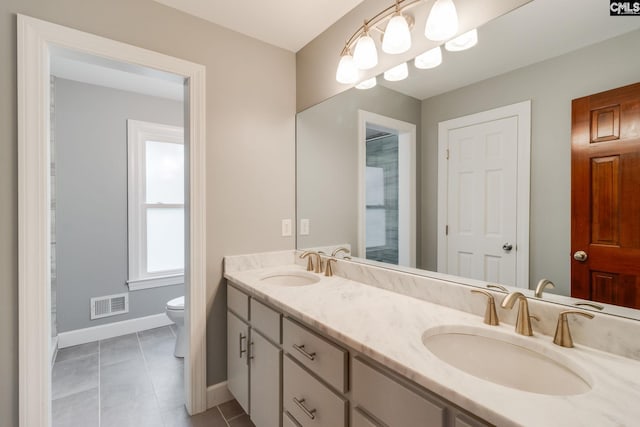 bathroom featuring baseboards, toilet, double vanity, and tile patterned flooring