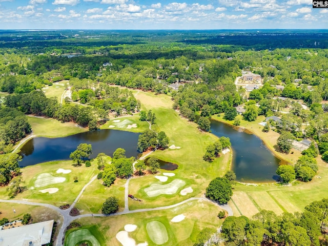 view of property location featuring a large body of water, a golf course, and a heavily wooded area