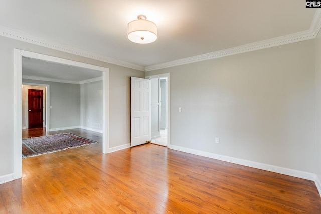 spare room featuring light wood-type flooring, ornamental molding, and baseboards