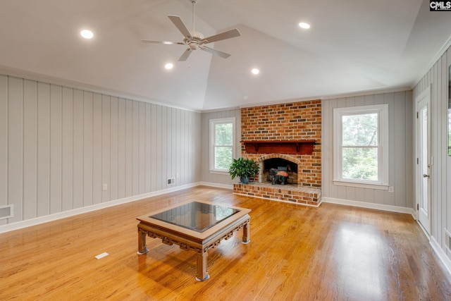 living room featuring wood finished floors, a ceiling fan, vaulted ceiling, a brick fireplace, and baseboards