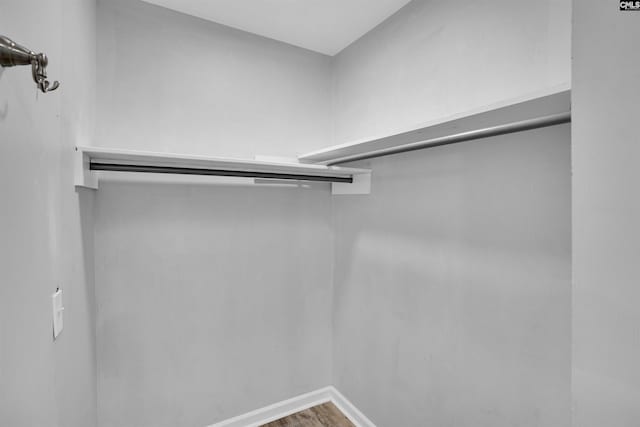 walk in closet with wood finished floors