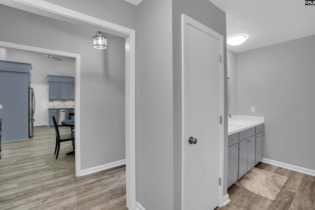 bathroom featuring wood finished floors, ceiling fan, vanity, decorative backsplash, and baseboards