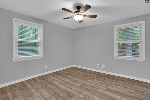 unfurnished room with wood finished floors, a ceiling fan, baseboards, and a textured ceiling