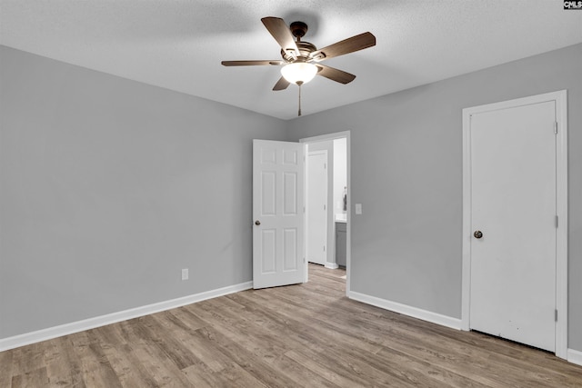 unfurnished bedroom featuring light wood-type flooring, baseboards, a ceiling fan, and a textured ceiling