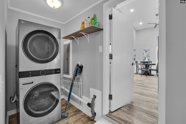 clothes washing area with stacked washer / dryer, wood finished floors, ornamental molding, baseboards, and ceiling fan