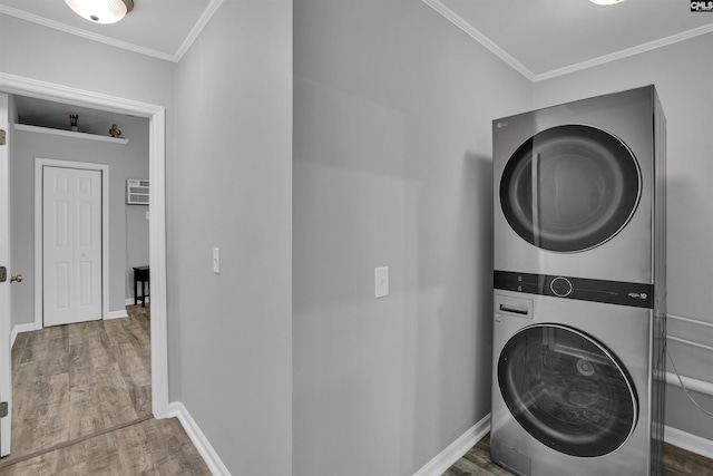 washroom featuring stacked washing machine and dryer, wood finished floors, baseboards, and crown molding